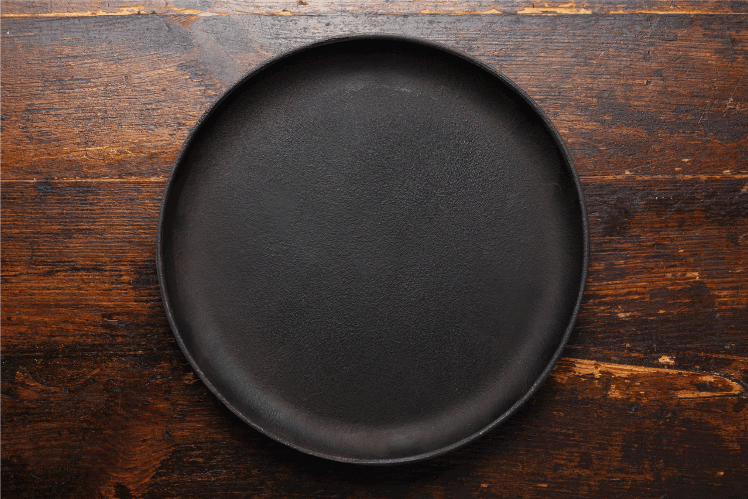 棕色木制背景上的圆形铸铁锅