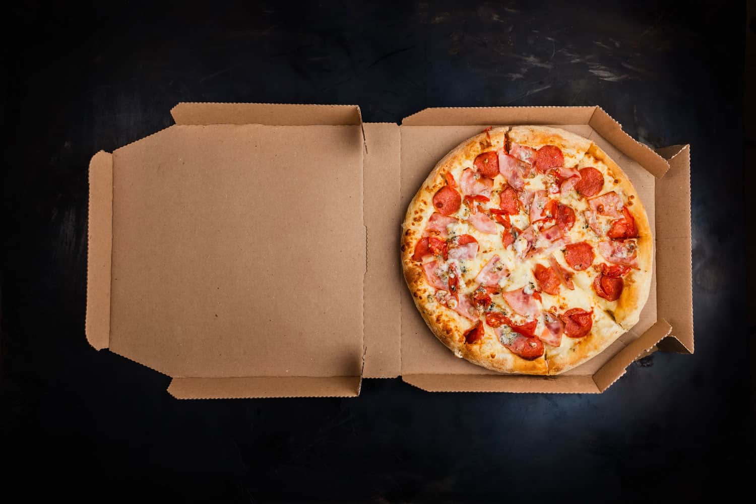 披萨装在深色背景的纸板箱里