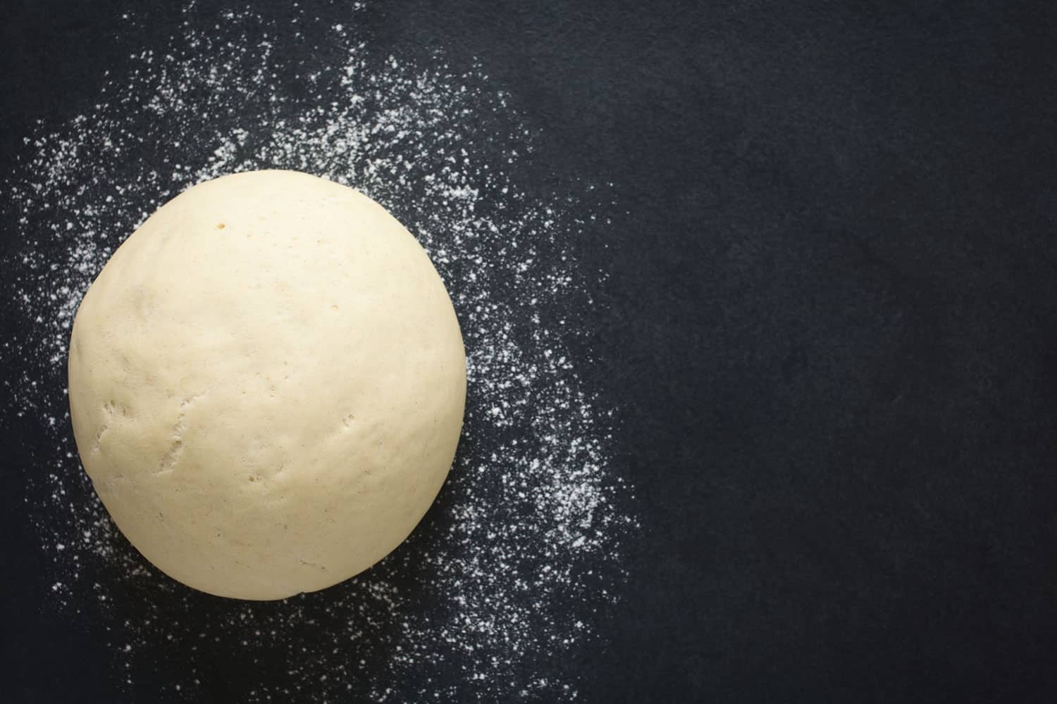 在石板表面撒上面粉制成面包或披萨的发酵面团