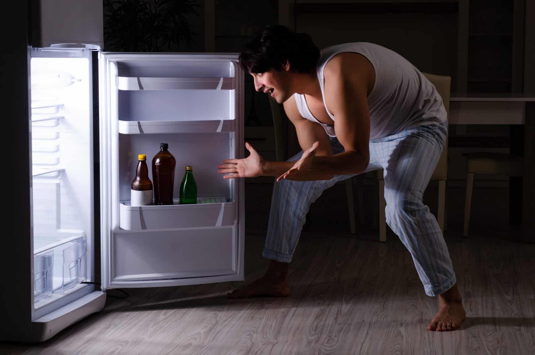 男人晚上在冰箱旁打破饮食