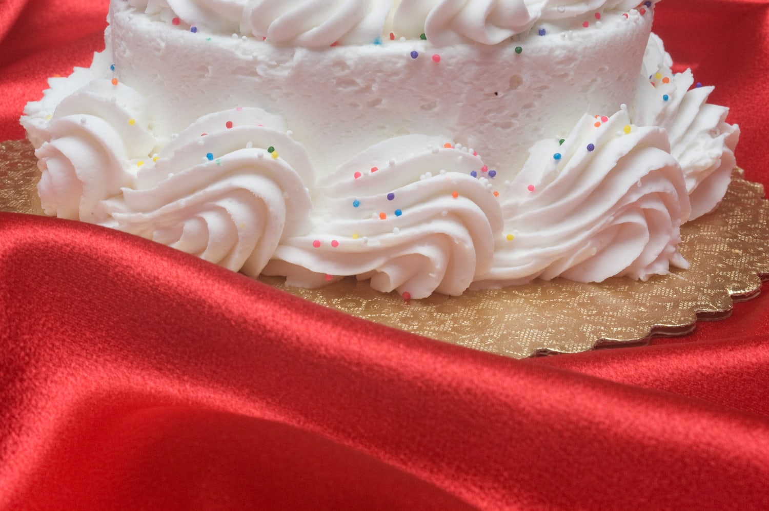 在一波又一波的红色缎子布中间有一个磨砂蛋糕。