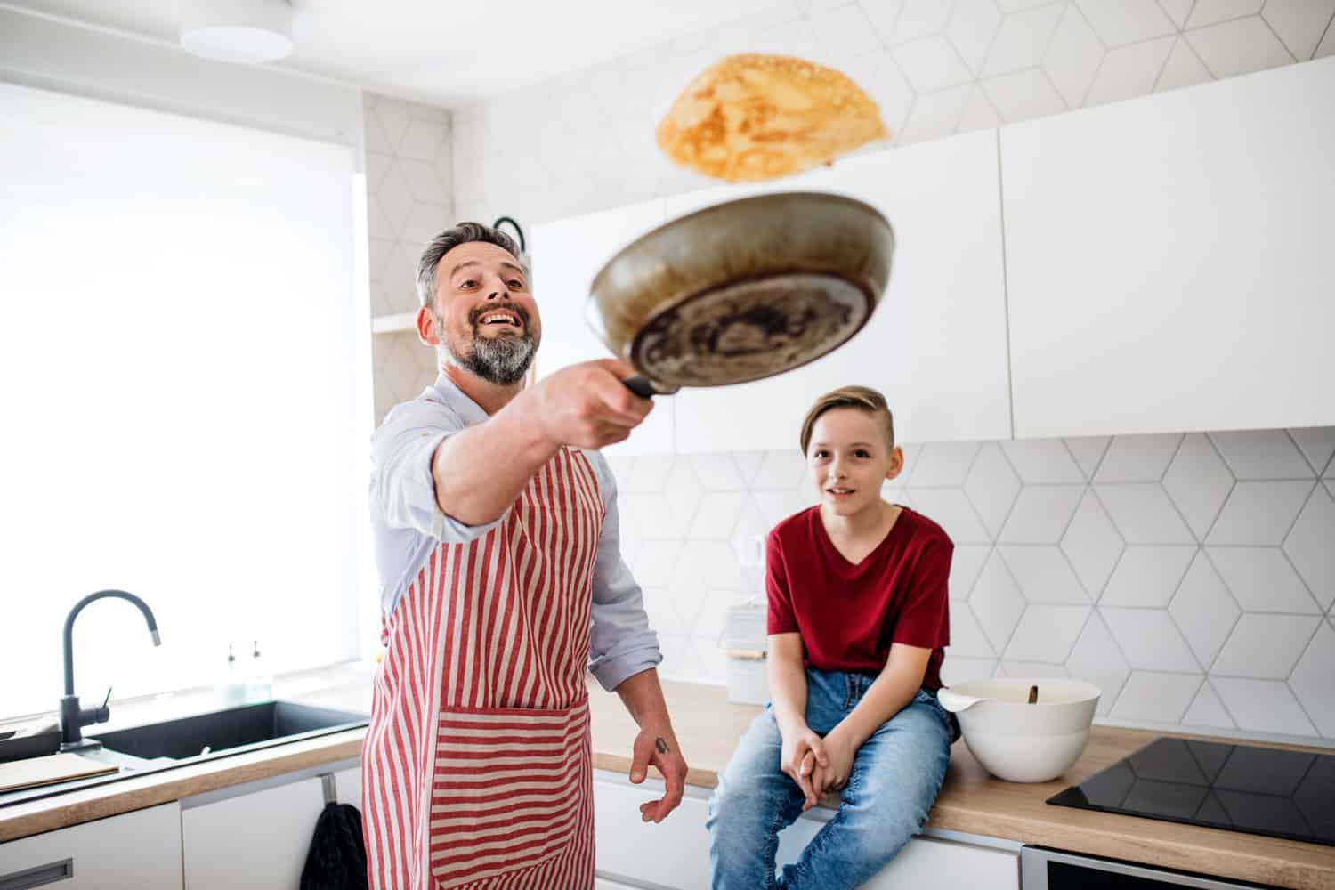 一个成熟的父亲带着小儿子在厨房里煎煎饼。bd手机下载