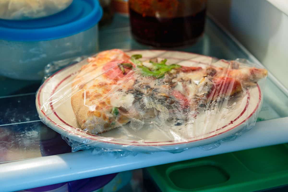 冰箱里裹着保鲜膜的一片披萨”width=