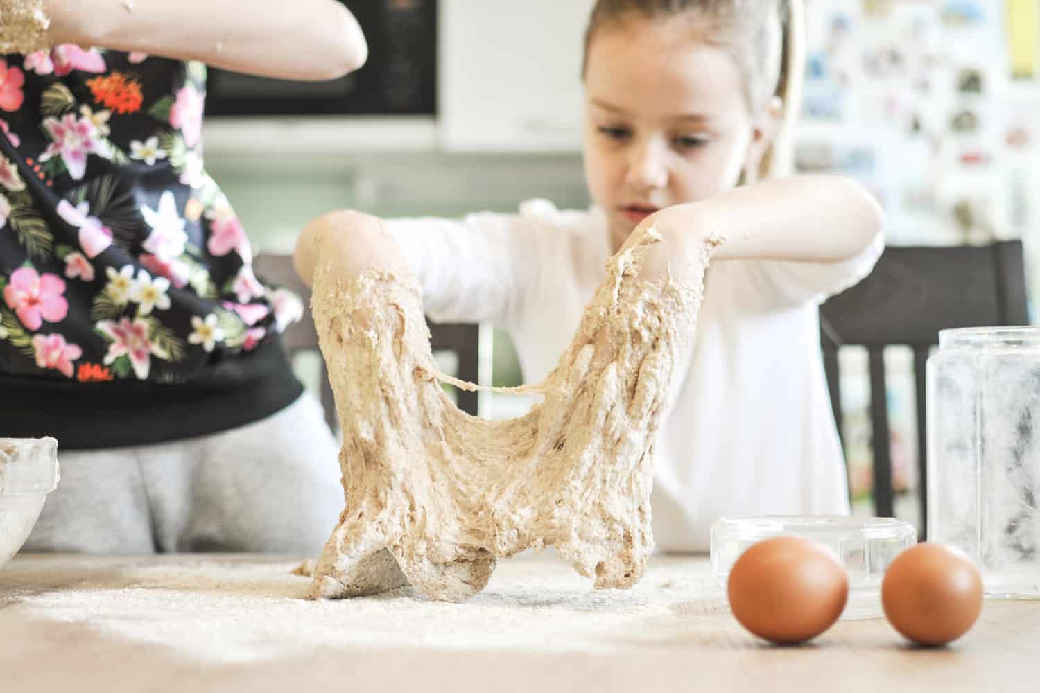 可爱的小女孩开心而使面团for a bread or pizza in a domestic kitchen.