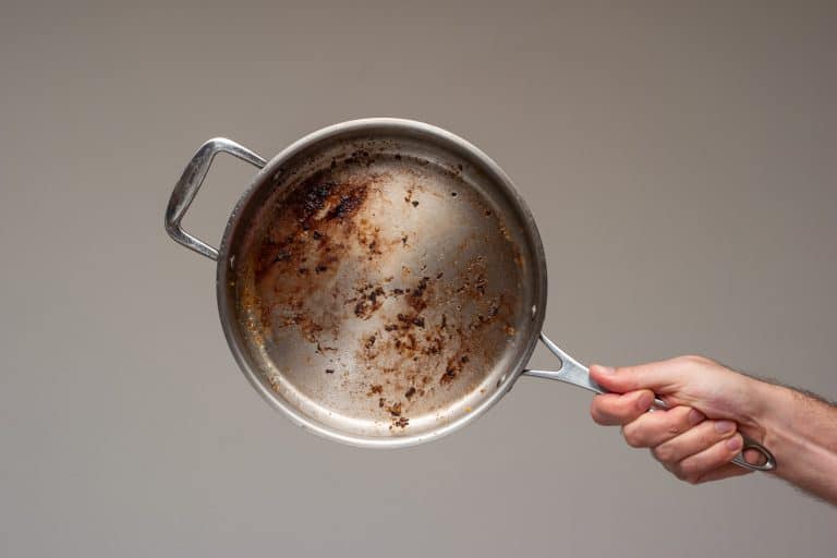 脏油烧金属煎锅在男性手举行。——如何防止煎饼附着在不锈钢锅