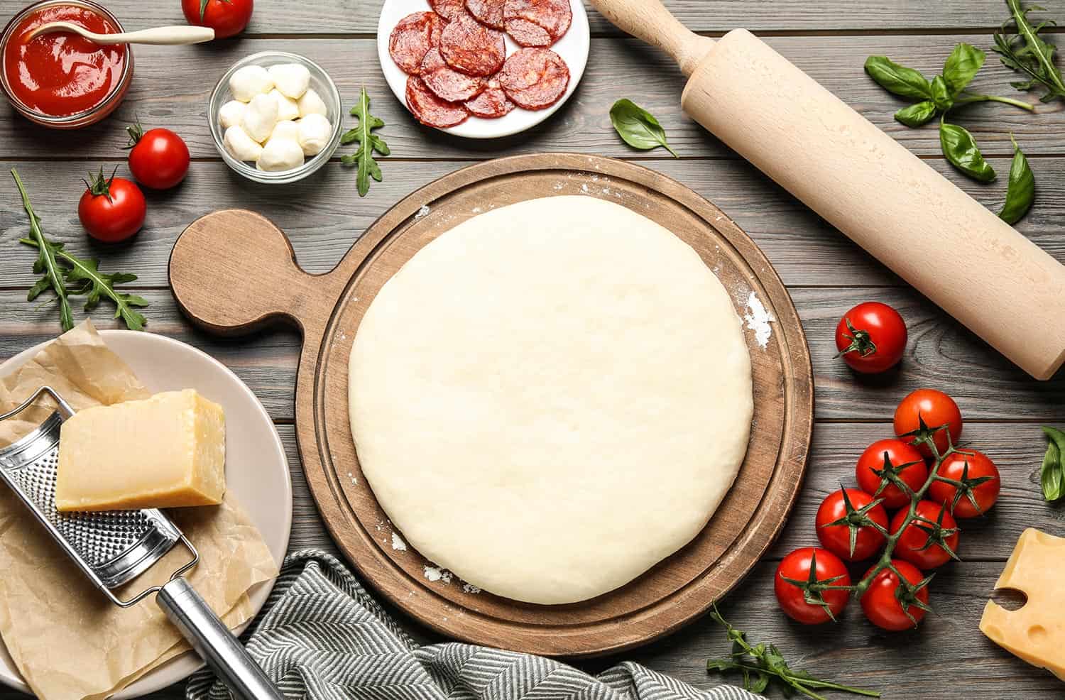 用生面团和新鲜食材制成的意大利辣香肠披萨放在木桌上＂width=