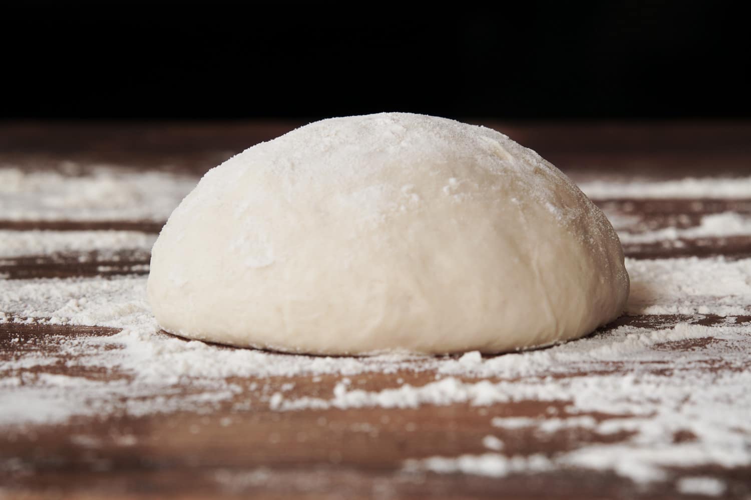 Homemade yeast dough ball for pizza on floured wooden table