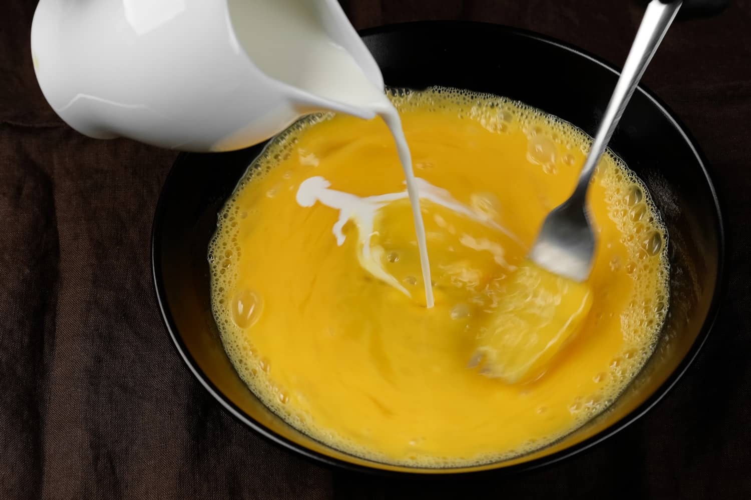 用叉子倒牛奶和搅拌鸡蛋。炒鸡蛋，煎蛋卷
