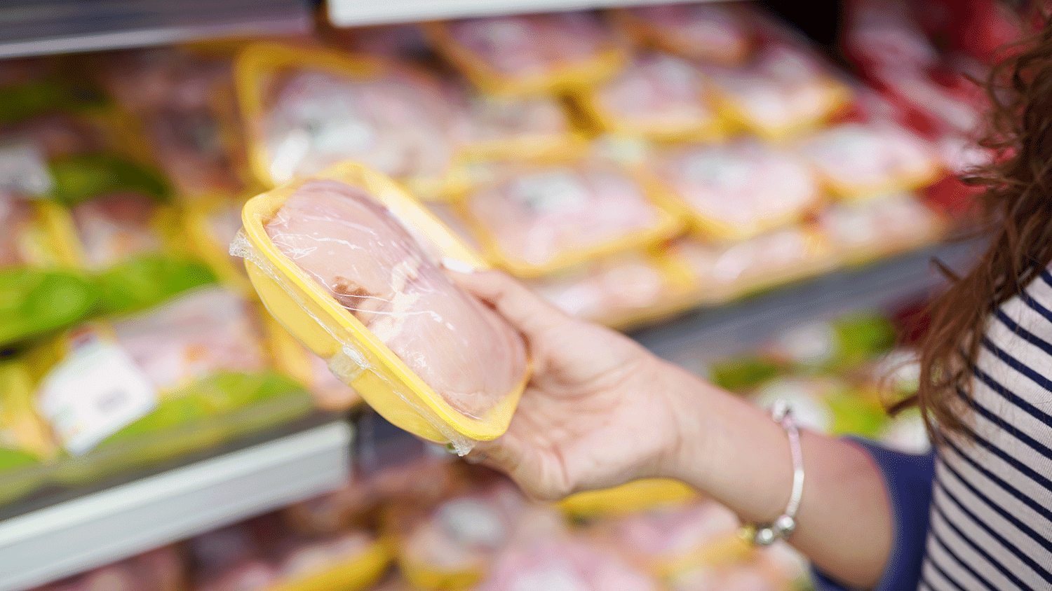 女人选择包装新鲜鸡肉在超市