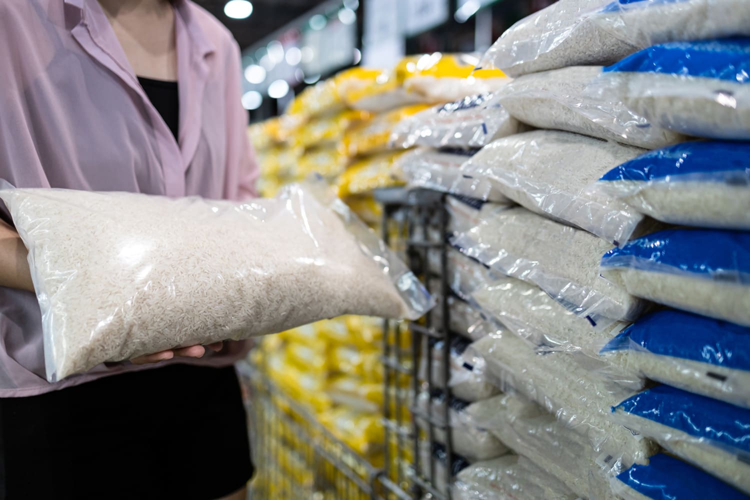 近距离的手，亚洲女性消费者拿着白米，购买干货，女孩购买透明塑料袋里的茉莉花米，选择在超市出售的生米产品，食物营养