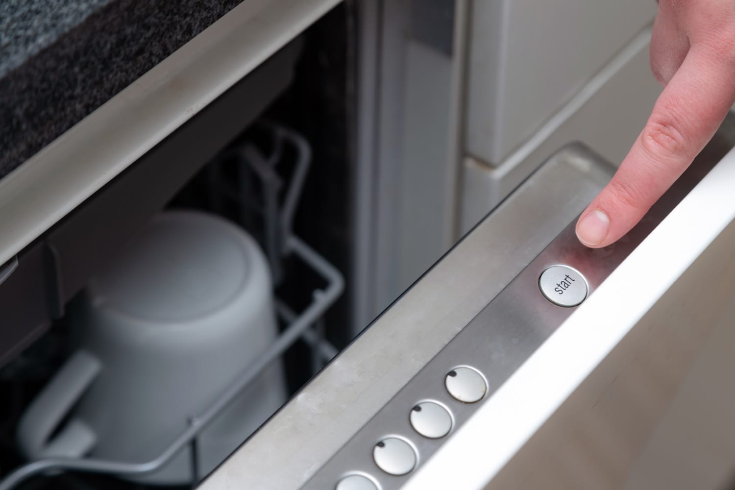 近距离手指按下厨房洗碗机上的启动按钮。bd手机下载手动启动洗碗机