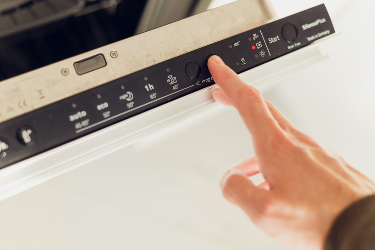 在洗碗机的控制面板上，人们正在选择生态模式程序