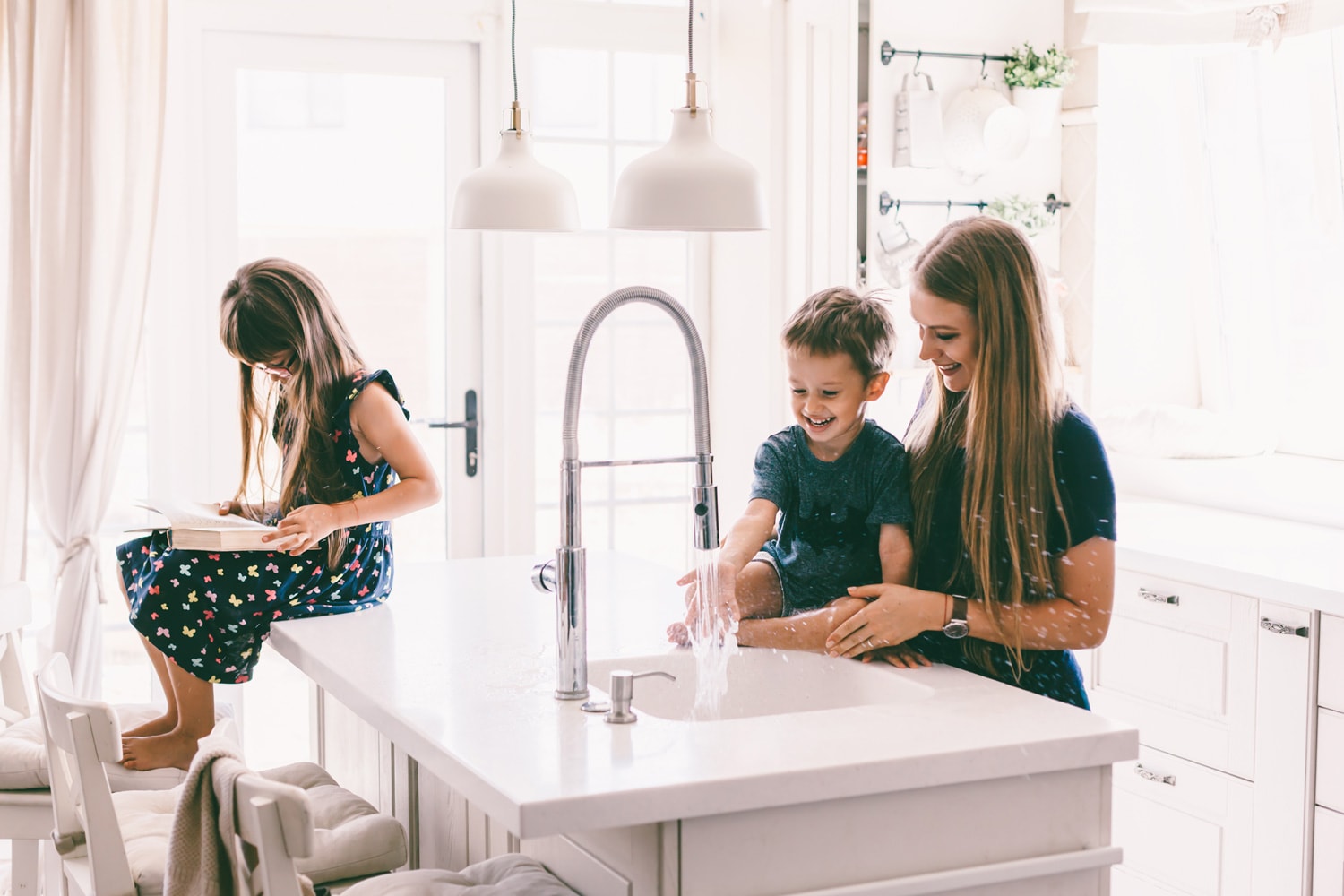 母亲和她的孩子们玩水在家里厨房水槽。bd手机下载幸福的生活家庭的时刻。