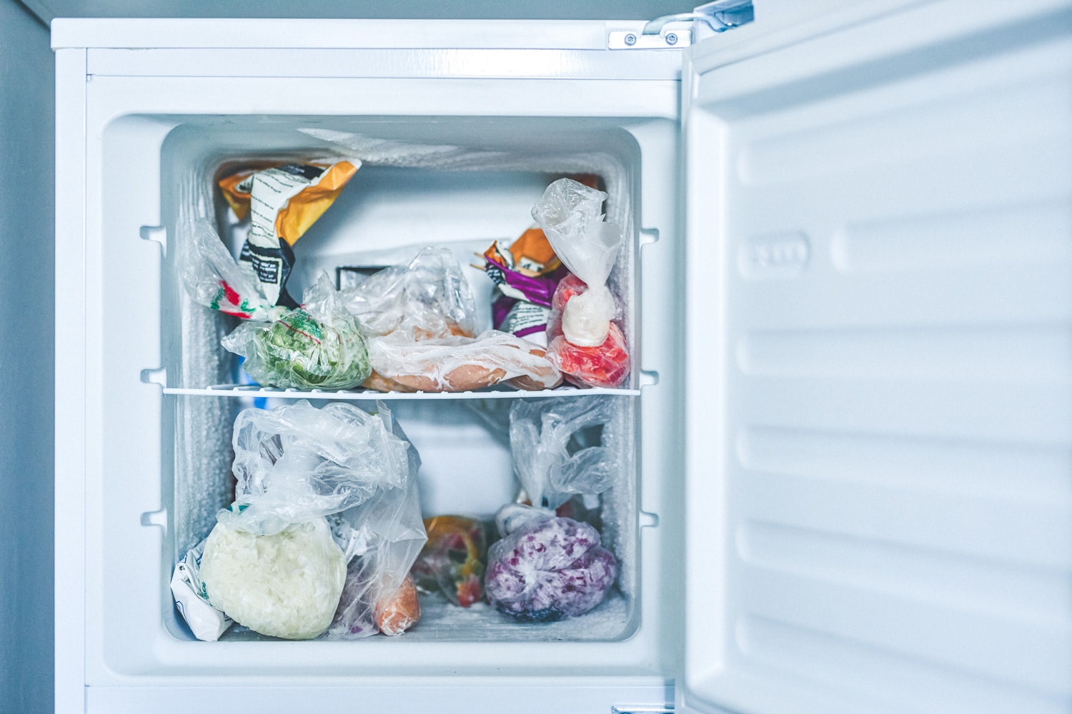 一个打开的冷冻室，用塑料袋装着冷冻食品