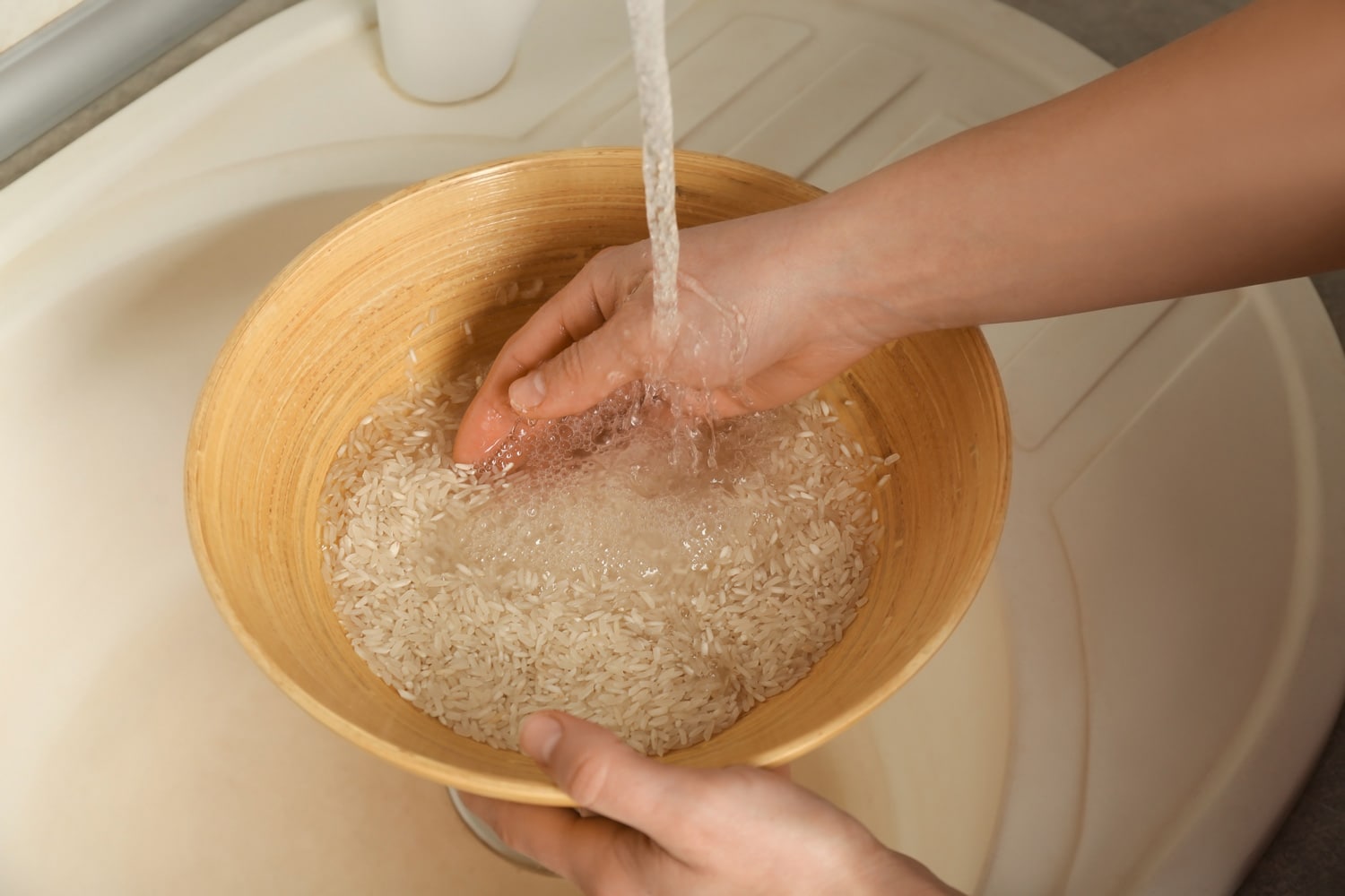 一名妇女用自来水在碗里冲洗米饭