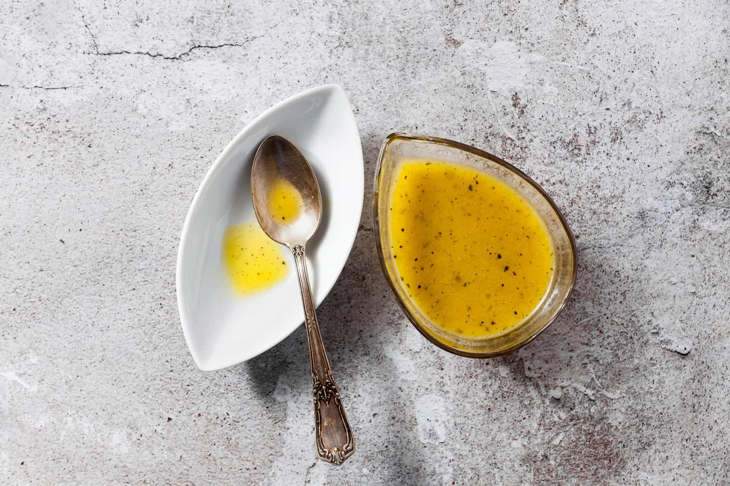 沙拉用橄榄油和柠檬调制的调料，盛在盘子里，银勺放在石桌上