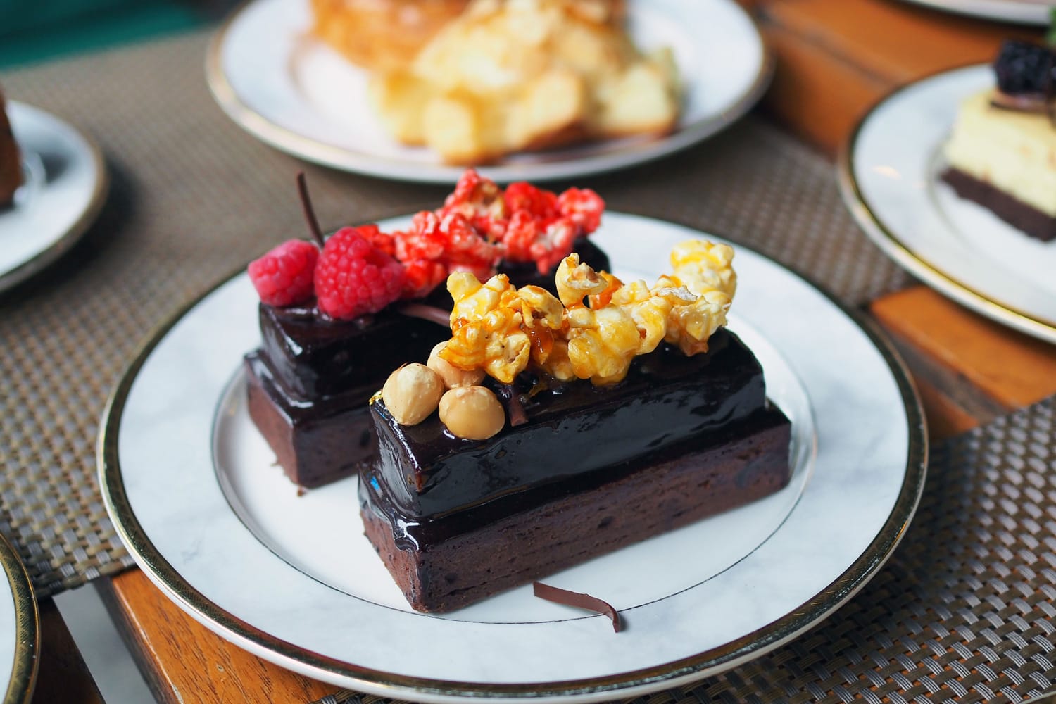 一盘美味的自制黑巧克力蛋糕;上面有焦糖爆米花和坚果，草莓爆米花和覆盆子＂width=