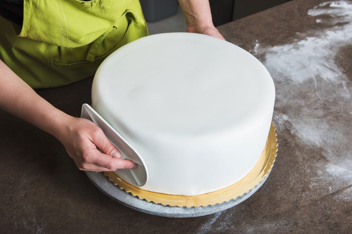 一个女人正在塑造一个完美光滑的皇家冰蛋糕