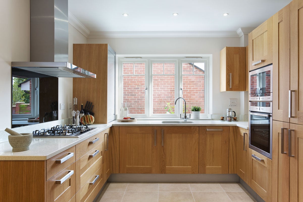 漂亮的厨房在一个现代bd手机下载化的公寓，橡木橱柜和抽屉和奶油色花岗岩工作台面＂width=