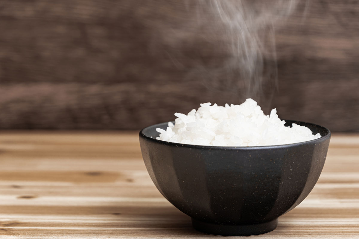 热的日本白米饭在一个黑碗里，放在木制的光桌上