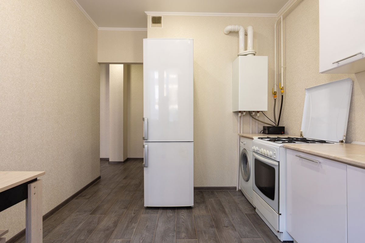 狭窄的米色客厅里有一个白色的小冰箱
