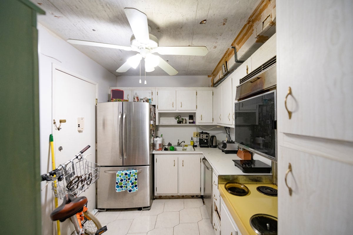 一个小公寓厨房的内部，白色的墙壁和橱柜和冰箱在一侧bd手机下载