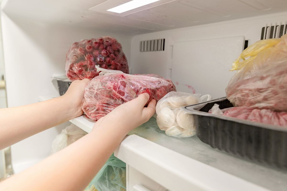 为了长期保存，一名妇女将冷冻水果产品放入冷冻室。