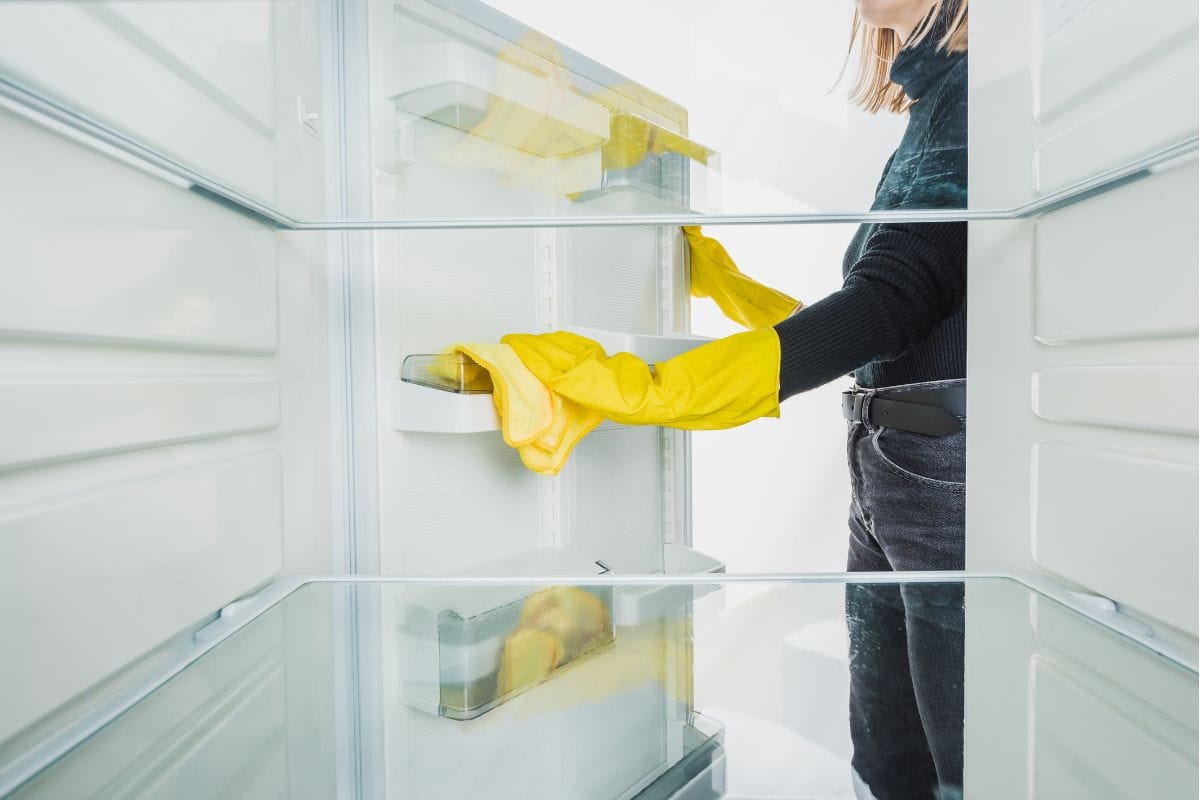 裁剪的观点，妇女清洁冰箱架上孤立的白色