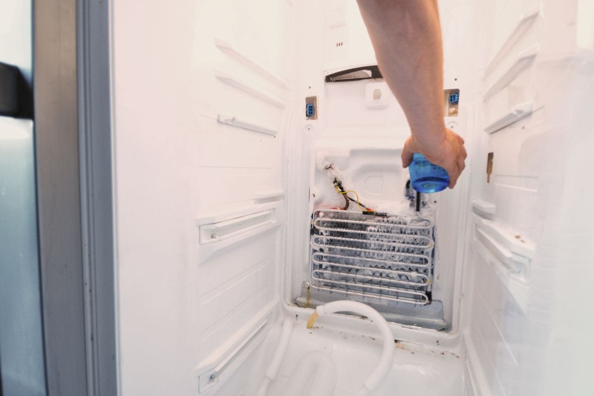 “男子修理冰箱的手，把热水倒在完全结冰的元件上，以迅速解冻。更多的冰箱修理镜头”