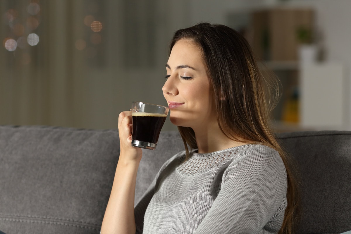 一个女人晚上坐在家里客厅的沙发上，享受着一杯咖啡