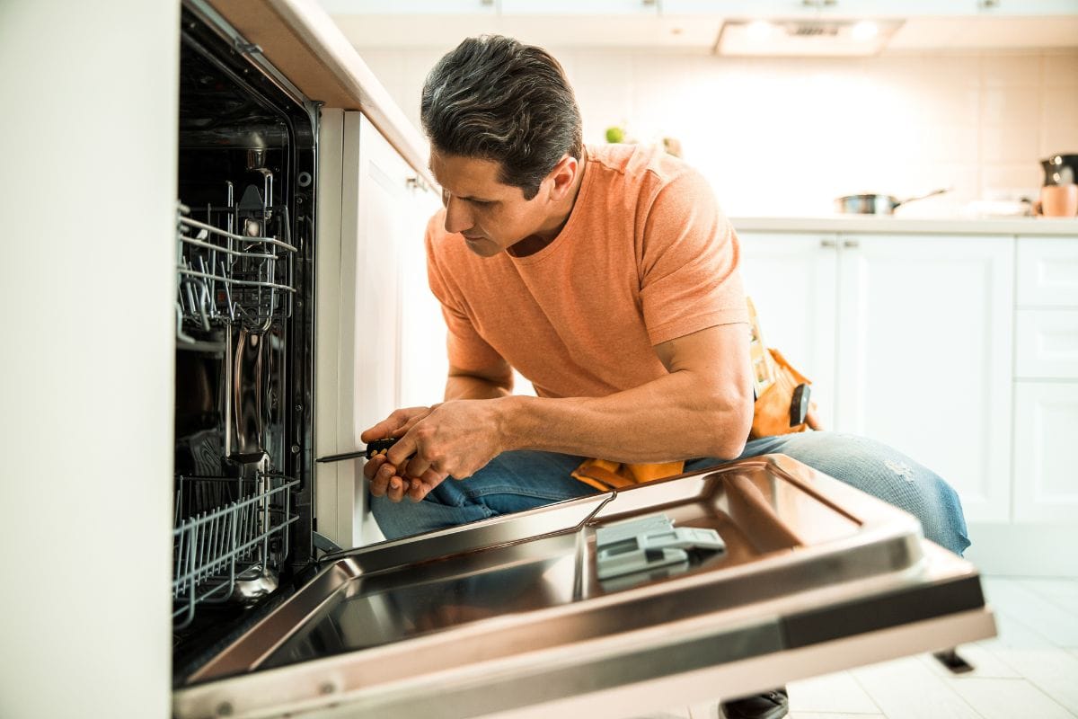 工人使用螺丝起子修理洗碗机在家里库存图片