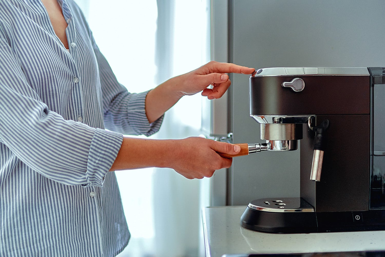 女性手握过滤器，在家里用现代咖啡机制作新鲜芳香的咖啡