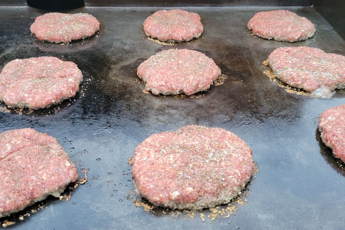 在佛罗里达，大量的生牛肉调味汉堡在调味的煎锅上烤着