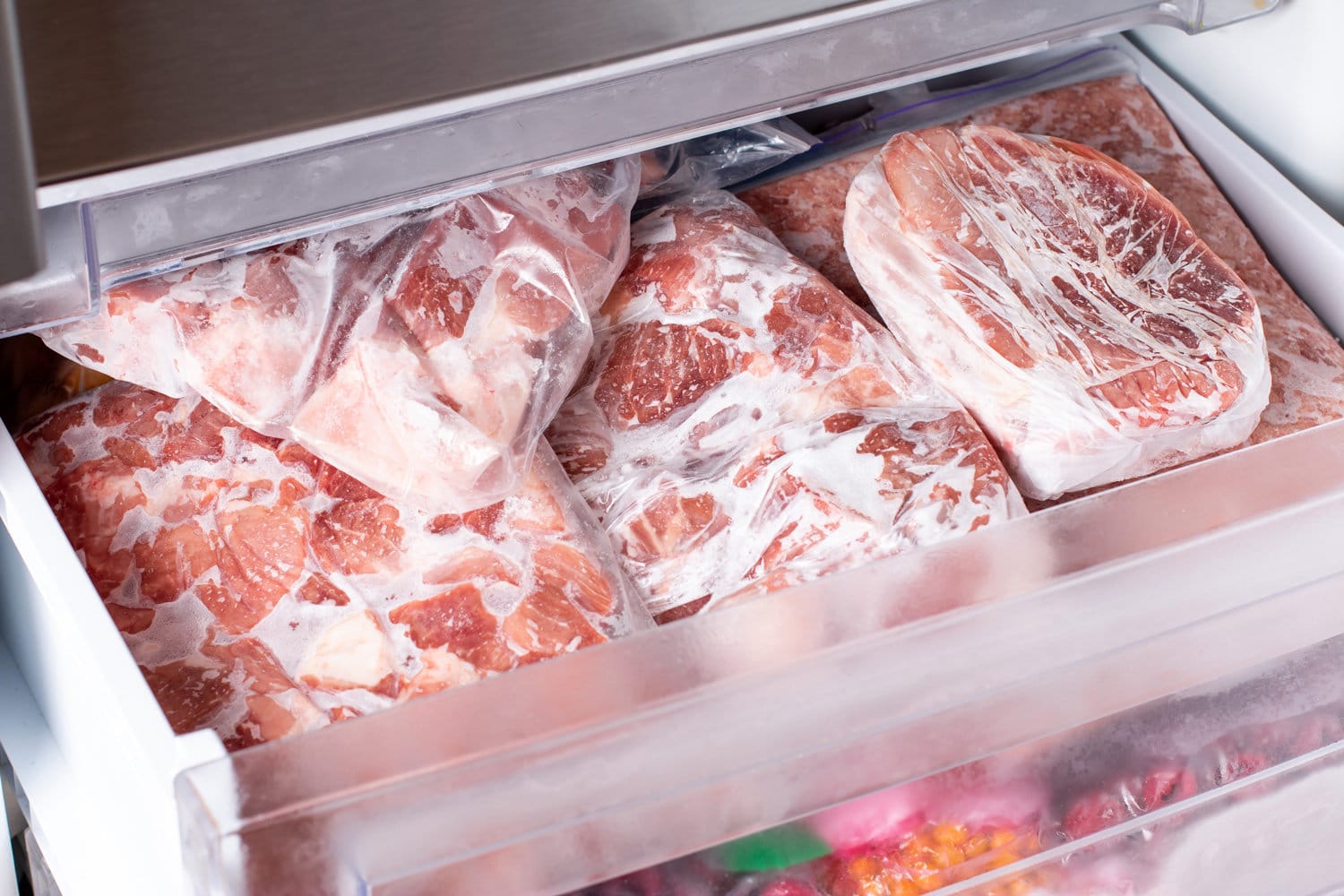 肉在冰箱冷冻室背景。冷冻室的猪肉、肉和鸡腿特写。冷冻食品
