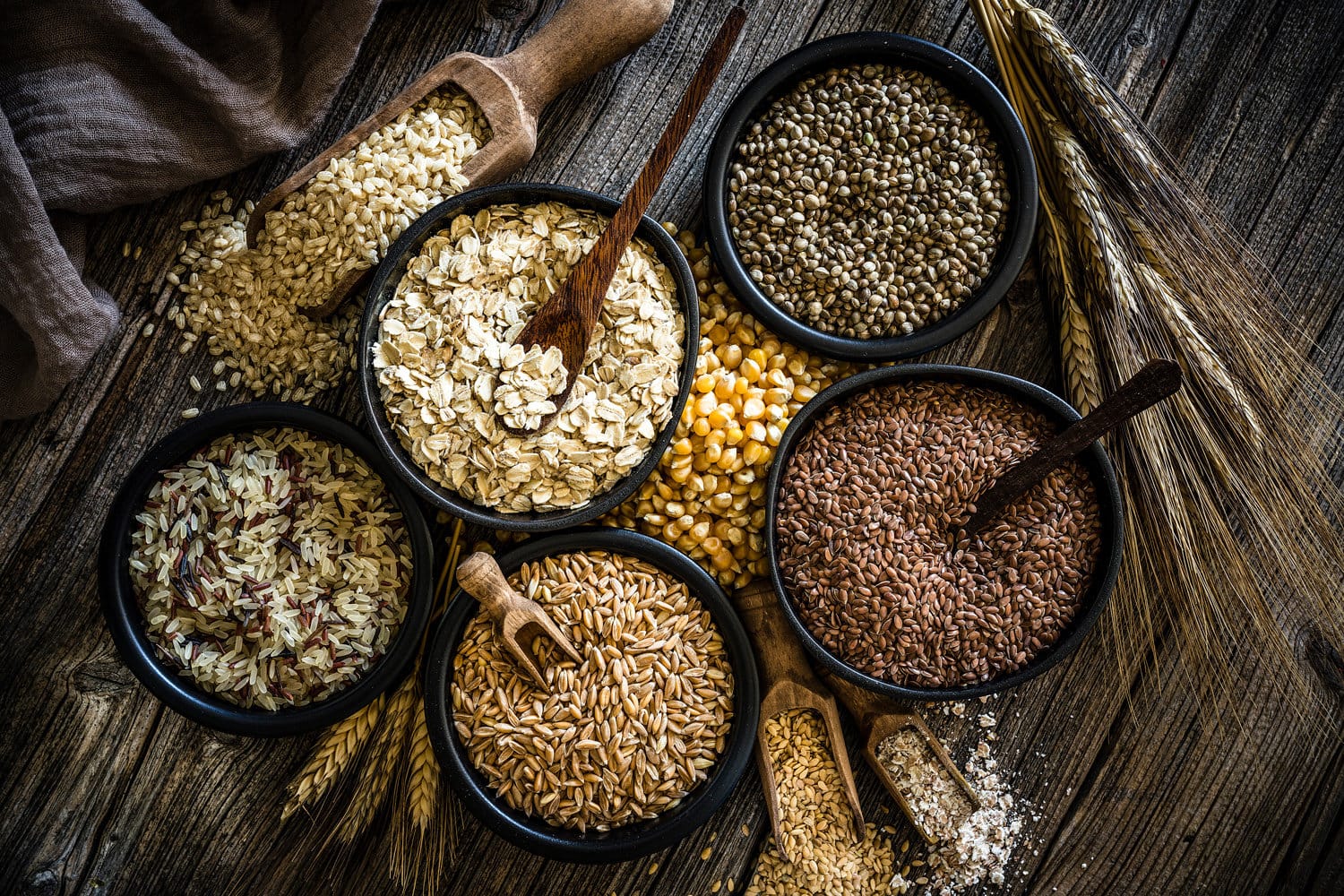 顶视图的全谷物和谷物成分在乡村木桌上。这种类型的食物是丰富的纤维和节食是理想的。成分包括燕麦片、糙米、玉米、干拼写,大麻种子和亚麻籽。主要的颜色是棕色的。