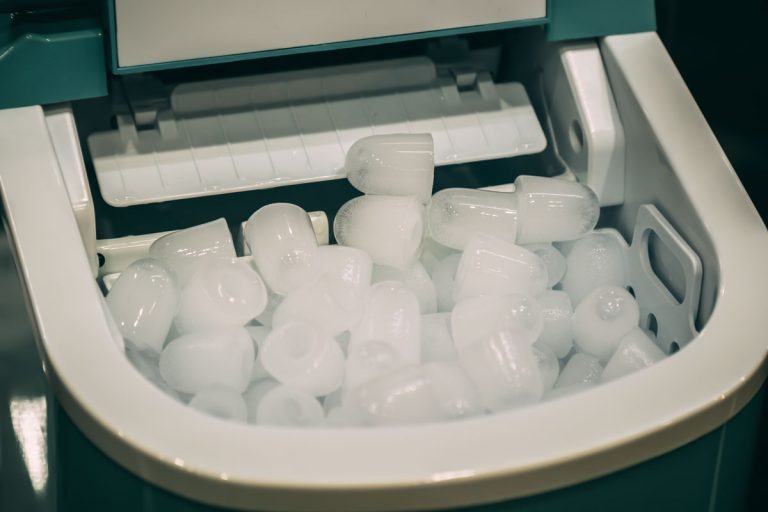 近距离照片的便携式迷你制冰机许多冰块绿色制冰机便携式，你应该关闭你的便携式制冰机[或你可以让它一直开着]?