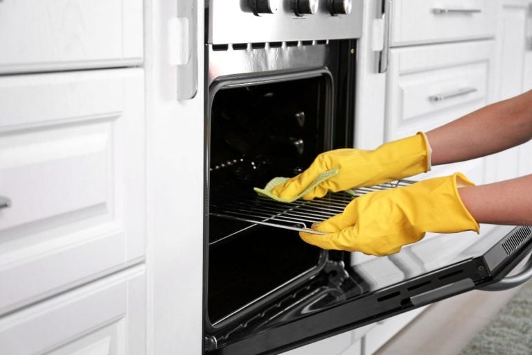 女人清洁烤箱在厨房。bd手机下载——烤箱清洗需要多长时间?