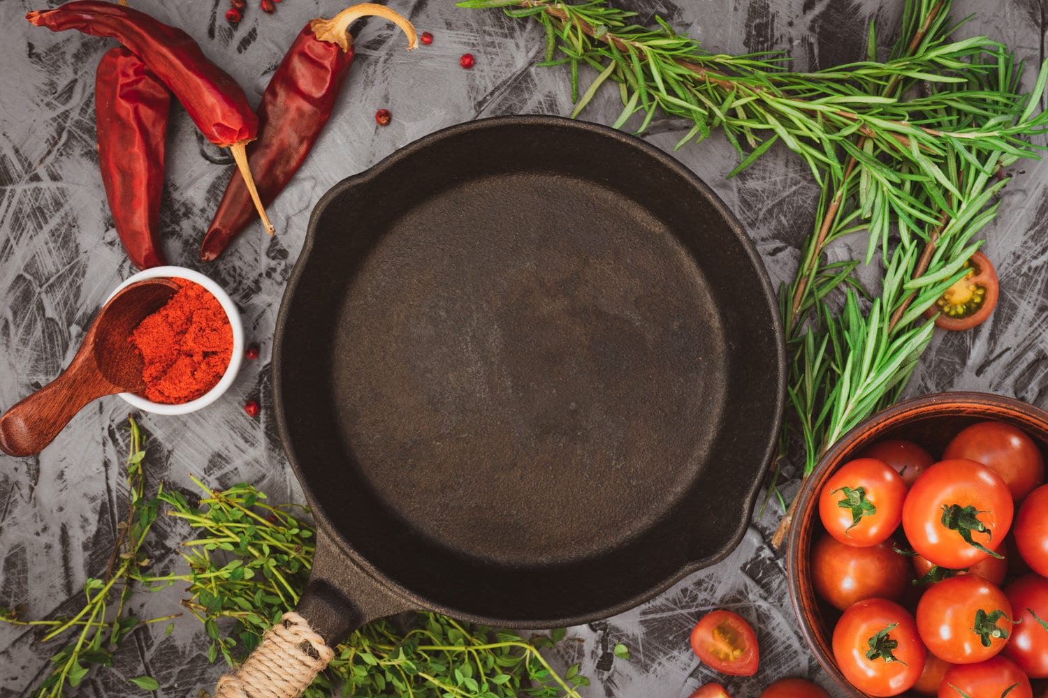 铸铁锅在混凝土背景与红熟番茄和红辣椒