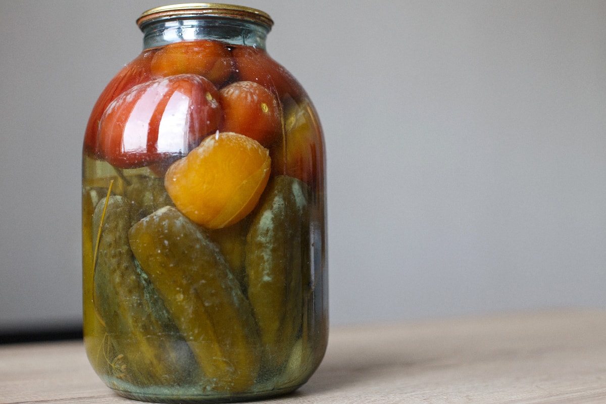 玻璃罐里有自制的腌制西红柿和黄瓜，上面有白色的木耳和霉菌