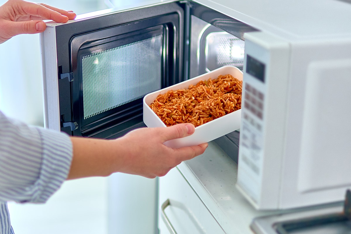 手在现代微波炉里加热食物容器