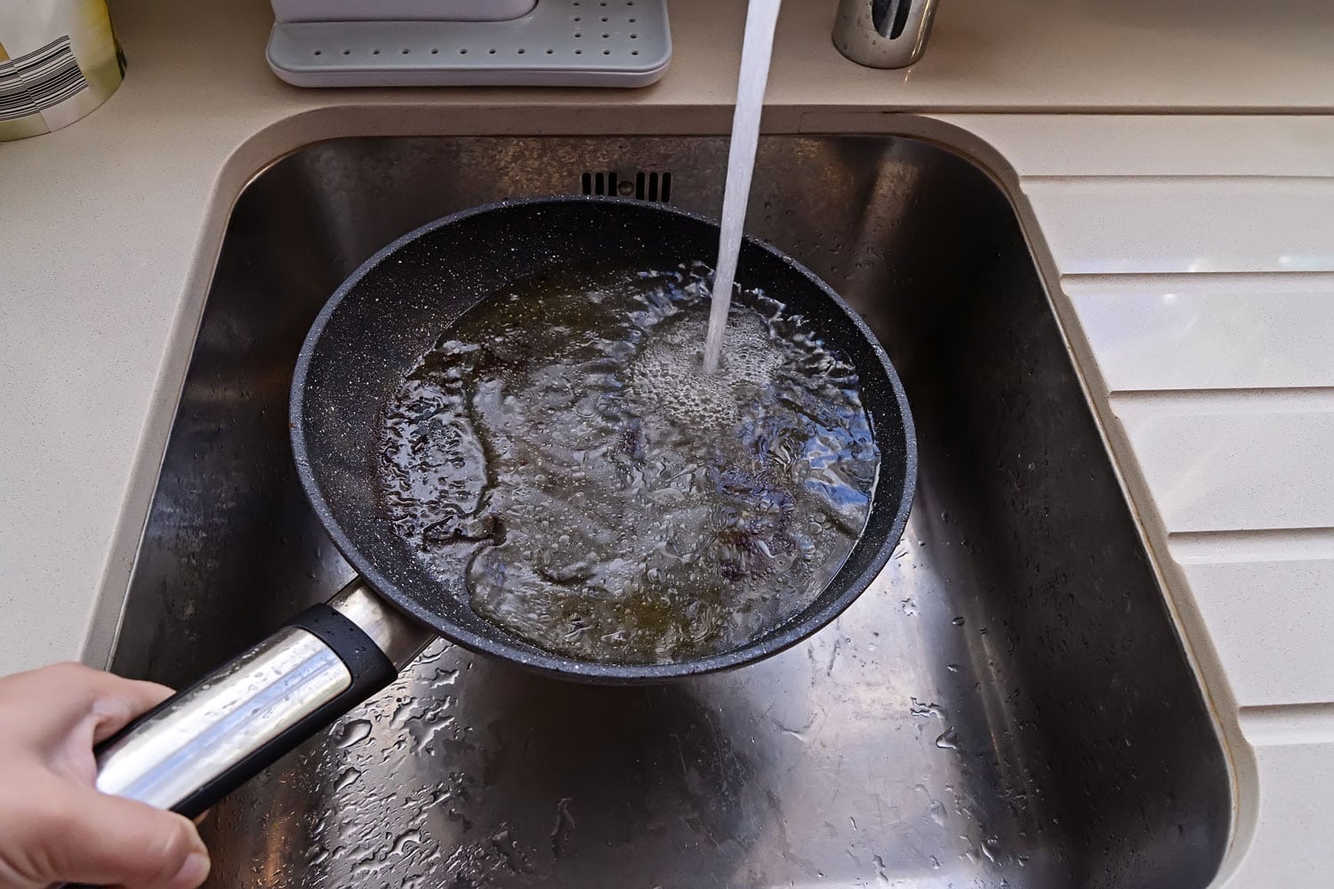 不粘表面煎锅的POV，热油在水龙头下在水槽中流动。关爱厨具概bd手机下载念