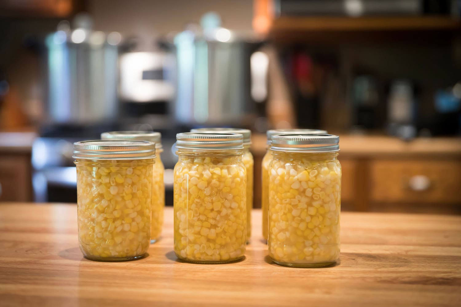 一品脱的玉米罐放在柜台上，准备进入压罐，压罐放在背景的炉子上。