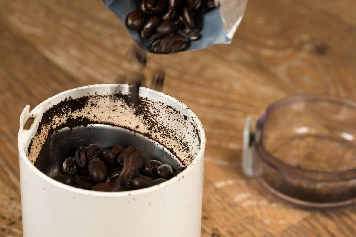 宏观的咖啡豆流入电磨机站在古老的木制餐桌。bd手机下载