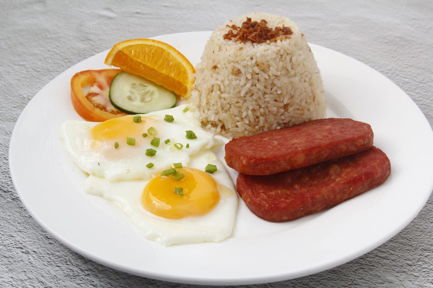 新鲜烹制的菲律宾食物“spam silog”或午餐肉片、鸡蛋和炒饭的照片。