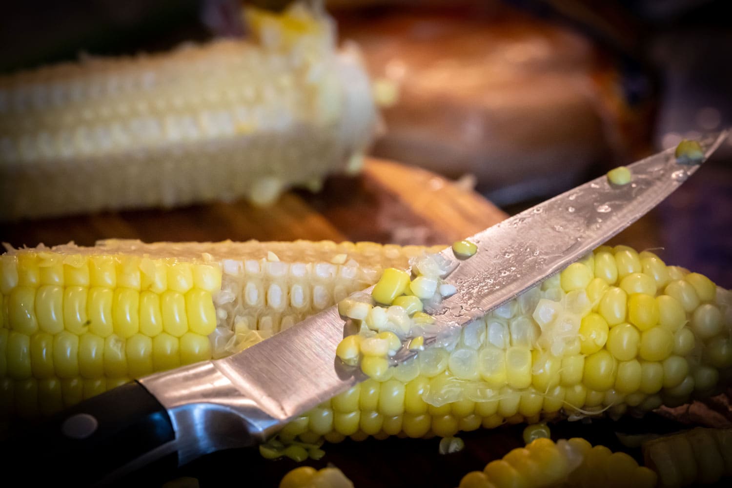 用刀将内核从甜玉米穗轴的一只耳朵。