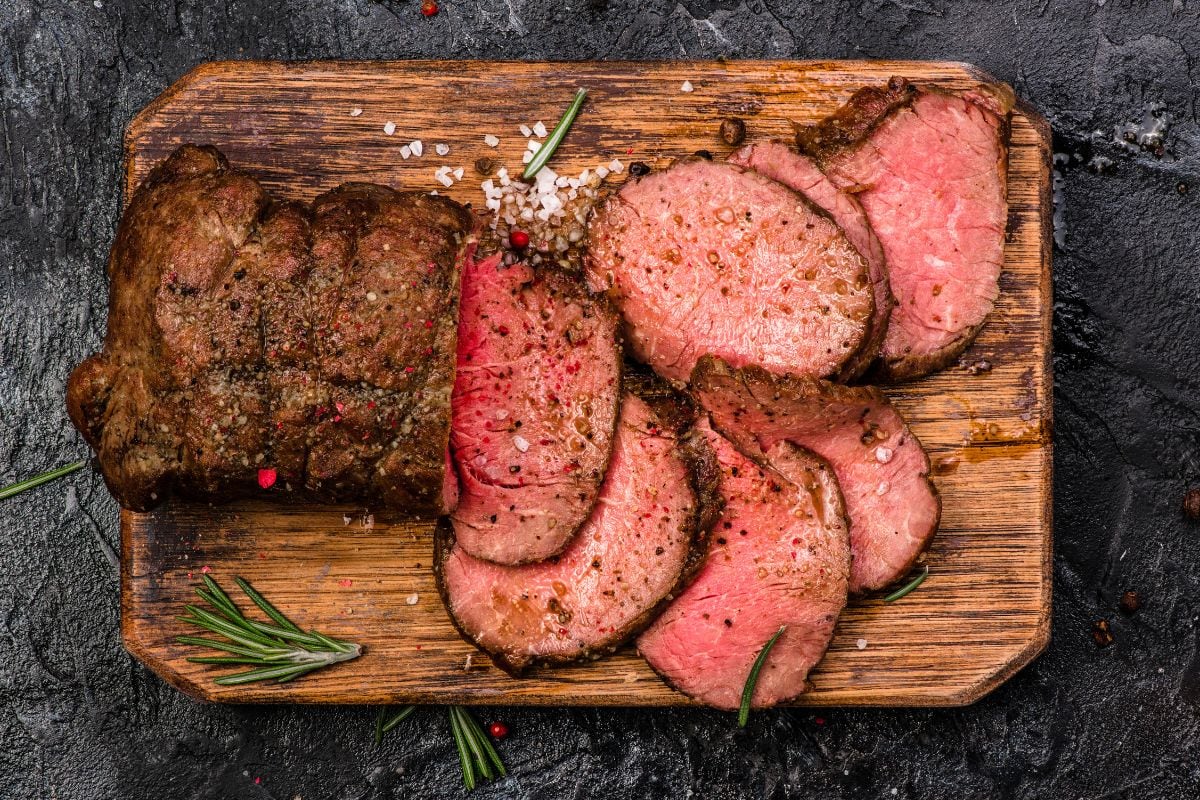 烤牛肉砧板上用盐和胡椒调味。前视图。