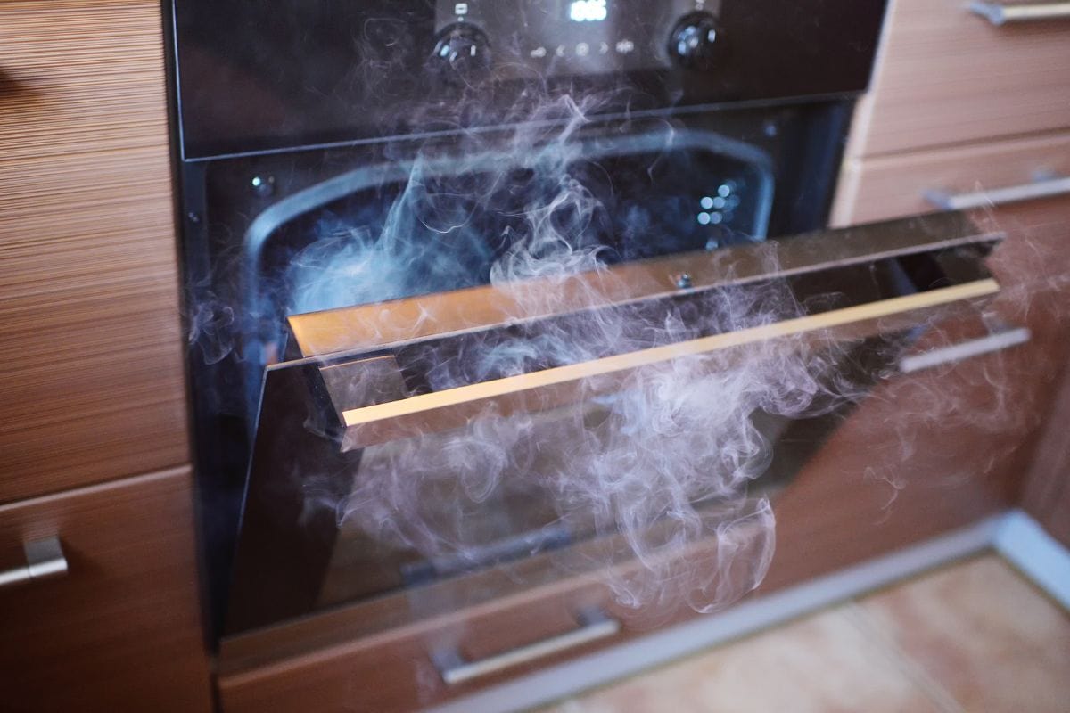 烟从厨房的烤箱的特写镜头。bd手机下载烧焦的食物。模糊图像的烤箱门的把手。